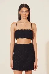 Top negro con tirantes finos y textura de flores en relieve.