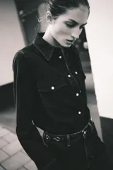 Jeans de tiro alto, pierna ancha y corte recto, confeccionado en denim de algodón rígido de color azul medio. Presenta un detalle de herrajes metálicos en la cintura.