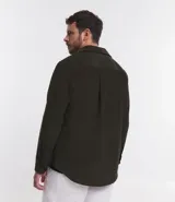 Camisa de hombre color verde oscuro, confeccionada en terciopelo, con cuello clásico, manga larga y dos bolsillos frontales con solapa y botón. Cierre frontal con botones.