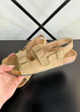 Sandalias planas color marrón claro con dos tiras anchas con hebillas y tira trasera.