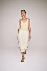 Falda midi de tiro medio, color beige, con detalle de combinación de tejidos a contraste y volante plisado semitransparente en el bajo. Cuenta con cierre lateral de cremallera oculta.