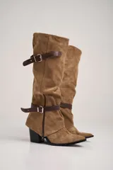 Botas texanas de caña alta color marrón, confeccionadas en cuero. Presentan dos correas de cuero con hebillas metálicas, cierre lateral y taco cuadrado. El largo de la caña es de 39 cm y el alto del taco es de 10 cm.