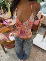 Top halter color salmón, de escote profundo en V y espalda abierta, con tirantes finos para atar al cuello. Cuenta con bordado floral artesanal y detalles de lentejuelas en tonos celestes, rosados y rojos.