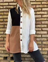Camisa larga de lino con diseño color block en blanco, negro y marrón. Tiene cuello camisero, mangas largas con puños abotonados y cierre frontal con botones de madera.