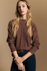 Polera de tejido de punto color marrón, con cuello alto y diseño de líneas verticales en el frente que aportan estructura. Presenta un calce relajado y mangas largas con puños ajustados.