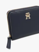 Billetera Tommy Hilfiger azul marino con cierre de cremallera y logo dorado TH en el frente. Cuenta con múltiples ranuras interiores para tarjetas y compartimento para billetes.