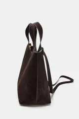 Bolso formato mini shopper confeccionado en piel de ante color topo. Cuenta con doble asa de mano, asa bandolera extraíble, cierre mediante botón imantado y bolsillo interior con cremallera.