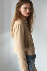 Chaqueta de cuello subido y manga larga, con cierre frontal de cremallera y botones a presión. Presenta bolsillos de vivo en el delantero y forro interior combinado.