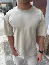 Remera de algodón pesado color beige, con corte oversize y cuello redondo. Presenta un pequeño bordado con el logo de la marca en el centro del pecho.