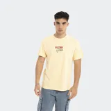 Remera amarilla de corte oversize con estampado frontal de la marca Reef y motivos playeros.