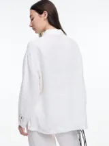 Camisa de lino 100% color azul marino, de manga larga y calce relajado. Presenta un bolsillo delantero invertido y un bordado tipo pespunte en color rosado que recorre el frente y el bolsillo.