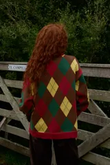 Buzo de tejido de punto con diseño de rombos en colores azul marino, amarillo, celeste y rojo. Presenta cuello redondo a la base, corte oversized y puños acanalados.