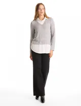 Buzo combinado de hilado fino color gris, con cuello en V y mangas largas. Presenta una pieza inferior y cuello tipo solapa en tela blanca que simula una camisa debajo.