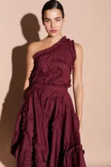 Top color bordó de un solo hombro, con volados decorativos en el escote y en el cuerpo de la prenda.