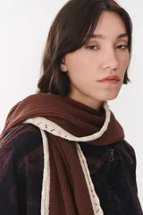 Bufanda de punto color marrón con capucha integrada y bordes en color crema. Presenta una etiqueta rectangular bordada con la palabra Anthea en uno de sus extremos.