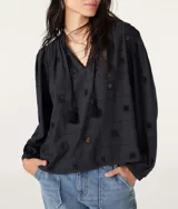 Blusa negra con bordados geométricos, escote en V con cordones y mangas largas.