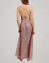 Vestido largo con estampado de ondas en tonos rosa y marrón, con detalles de encaje marrón en el escote y aberturas laterales, tirantes finos y tajo profundo en la pierna.