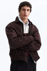 Campera marrón de tejido suave con acabado cepillado, cuello camisero, cierre frontal y bolsillos laterales.