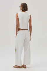 Chaleco blanco de gabardina con bordados florales y cierre frontal con botones forrados en la misma tela.