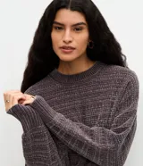 Suéter de punto chenille color gris, con textura acanalada, cuello redondo y mangas largas con puños ajustados.