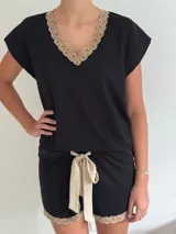 Pijama de algodón negro, compuesto por una remera de manga corta con escote en V y puntilla beige, y un short con elástico en la cintura, lazo decorativo beige y puntilla beige en el ruedo.