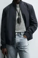 Cazadora de corte regular confeccionada en tejido técnico repelente al agua. Presenta cuello subido, manga larga con puños de rib, bolsillos laterales de vivo y cierre frontal con cremallera.