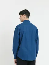Camisa de manga larga con cuello button-down, cierre frontal con botones y bolsillo parche en el pecho. Presenta un diseño de textura sutil en color azul.