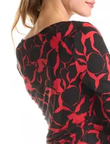 Vestido corto de seda fría con estampado floral en tonos rojo y negro. Presenta cuello volcado, mangas tres cuartos y un detalle de drapeado lateral en la cintura.