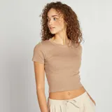 Camiseta cropped color beige de manga corta y cuello redondo.