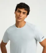 Remera deportiva de hombre con tecnología dry fit, cuello redondo y manga corta. Presenta un diseño liso en color beige con una pequeña etiqueta decorativa en el dobladillo.