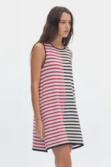Vestido midi de punto sin mangas con diseño de rayas, corte evasé. Presenta un diseño bicolor asimétrico: el lado izquierdo con rayas horizontales blancas y rojas sobre fondo celeste, y el lado derecho con rayas horizontales negras y blancas. Incluye un pequeño parche bordado en el pecho.