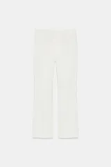 Pantalón tobillero de tiro medio, color blanco, con diseño flare o evasé en el bajo y bolsillos delanteros con cremallera oculta.