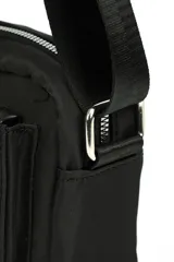 Bandolera de diseño rectangular en color negro, con cierre superior y bolsillo frontal con cierre. Incluye una correa larga ajustable para llevar al hombro o cruzada, y un detalle de tirador de cuerda trenzada en el bolsillo delantero.