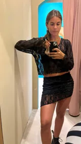 Blusa corta de encaje negro con mangas largas acampanadas.