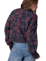 Buzo Caterpillar de cuello redondo en suave tejido french terry, de calce relajado y mangas largas. Presenta estampado floral completo en tonos azules y rojos, con el logo de la marca en el centro del frente y detalles de punto acanalado en puños, cuello y dobladillo.