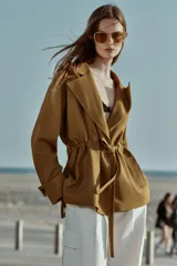 Chaqueta estilo trench corta color azul marino confeccionada con lino. Cuenta con cuello solapa, manga larga con trabilla, bolsillos delanteros de vivo y cierre frontal con lazada ajustable en la cintura.