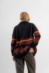 Saco de lana y poliamida negro con diseño geométrico en amarillo, rojo y marrón. Tiene silueta recta, largo debajo de la cola, bolsillos en los costados, escote polo y cierre frontal con botones.