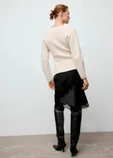Chaqueta de punto medio color beige, con cuello en V, cierre frontal con cremallera, diseño entallado y manga larga.