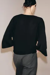 Top fluido de punto liso en color blanco, con escote en V pronunciado y mangas cortas amplias.