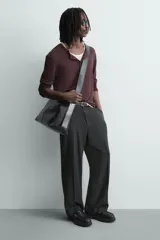 Mocasín negro de cuero liso con antifaz y flecos en el empeine. Presenta costuras blancas visibles y suela track gruesa de goma.