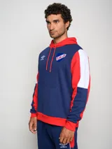 Canguro de felpa Umbro del Club Nacional de Football, con diseño tricolor en rojo, azul y blanco. Presenta capucha con cordones ajustables, bolsillo tipo canguro frontal, logo de la marca y escudo del club bordados en el pecho.