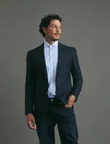 Saco de vestir azul oscuro con textura sutil, corte entallado, cierre frontal de un botón y solapas clásicas.