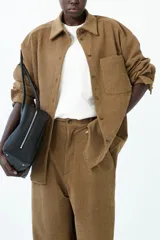 Sobrecamisa de textura acanalada color marrón, con cuello camisero, cierre frontal de botones y bolsillo de parche en el pecho.