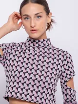 Top corto de tejido con estampado geométrico retro en tonos rosa, gris y negro. Es de manga larga con cut-out en los codos y cuello alto.