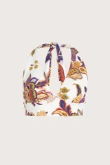 Top de bikini estilo halter con escote profundo y banda ancha bajo el busto. Presenta un diseño estampado con motivos botánicos y paisley en tonos cálidos y púrpura sobre fondo blanco.