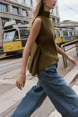 Top de punto color verde militar, con cuello subido y manga sisa. Presenta apliques dorados en los laterales y un bajo asimétrico.