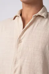 Camisa de manga corta confeccionada en lino, con cuello clásico y cierre frontal de botones. Presenta un corte relajado y textura liviana.