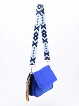 Bandolera roja de tela acolchada con solapa y cierre magnético. Incluye correa de hombro ajustable y extraíble, y detalle de borla de cordones de colores.