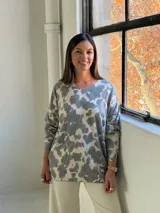 Sweater de punto con estampado de manchas irregulares, cuello en V y mangas largas con puños ajustados.