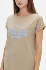 Remera de algodón color beige, de manga corta con vuelta, cuello redondo y corte holgado. Cuenta con un estampado frontal con la inscripción "Manhattan New York East Coast" en tonos celestes.